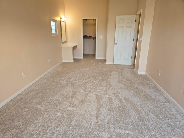 unfurnished bedroom featuring a spacious closet and light colored carpet