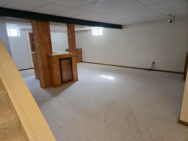 basement with light carpet, a paneled ceiling, and bar area