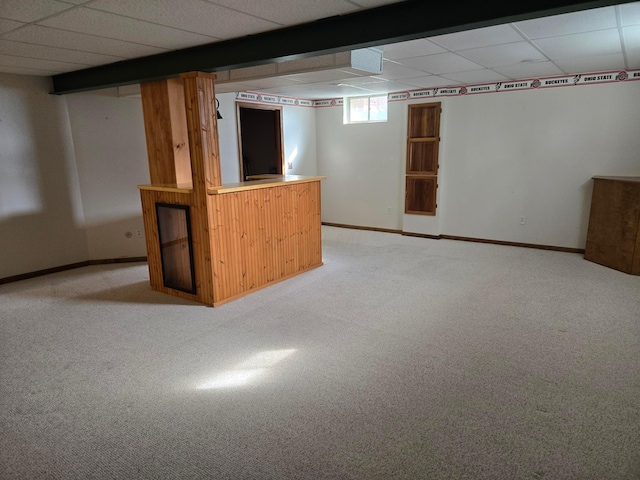 basement with a drop ceiling, light carpet, and bar