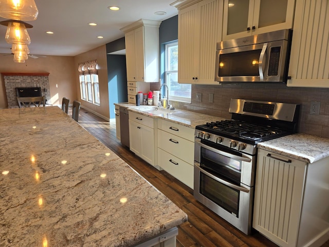 kitchen featuring light stone countertops, decorative light fixtures, dark wood-type flooring, and stainless steel appliances