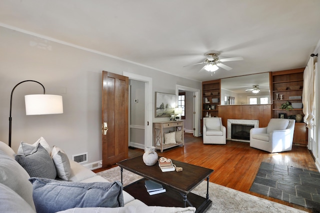 living room with hardwood / wood-style flooring, ornamental molding, and ceiling fan