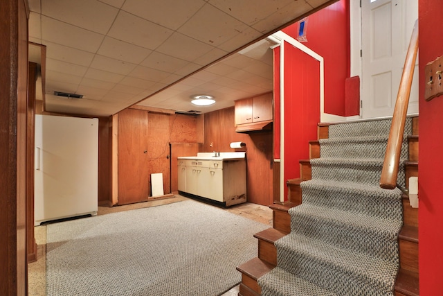 interior space with sink, a paneled ceiling, and wooden walls