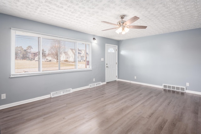 spare room with a textured ceiling, wood-type flooring, and ceiling fan