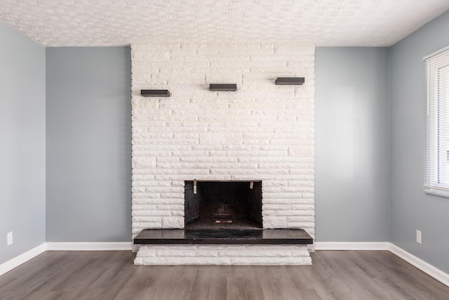 room details with a brick fireplace, hardwood / wood-style flooring, and a textured ceiling