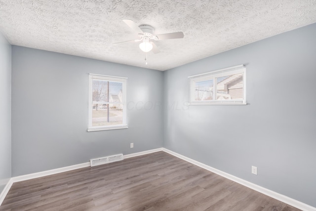 unfurnished room featuring ceiling fan, wood-type flooring, a textured ceiling, and a wealth of natural light