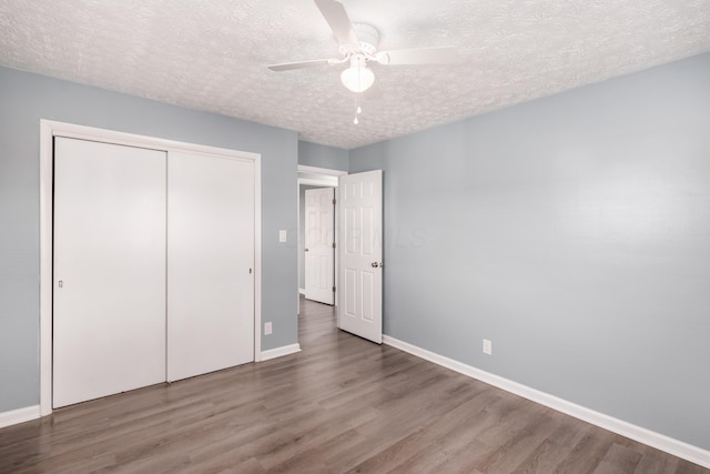 unfurnished bedroom with ceiling fan, hardwood / wood-style floors, a textured ceiling, and a closet