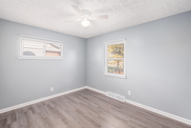 empty room featuring ceiling fan, a textured ceiling, light hardwood / wood-style floors, and a healthy amount of sunlight