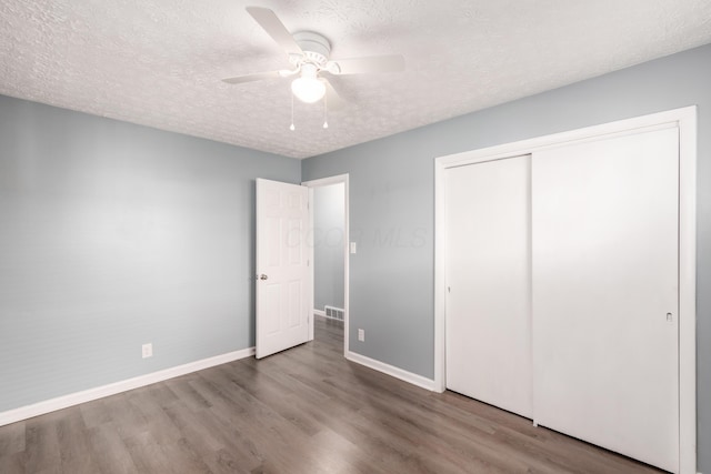 unfurnished bedroom with ceiling fan, a closet, a textured ceiling, and light wood-type flooring