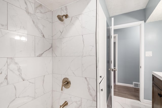 bathroom with vanity, a textured ceiling, and tiled shower / bath