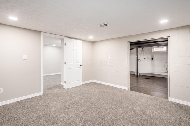 basement featuring a textured ceiling and dark colored carpet