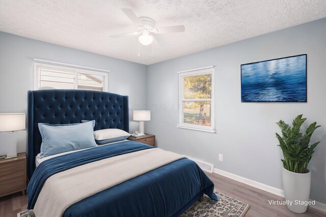 bedroom featuring ceiling fan, hardwood / wood-style floors, and a textured ceiling