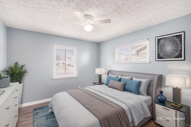 bedroom with multiple windows, a textured ceiling, wood-type flooring, and ceiling fan