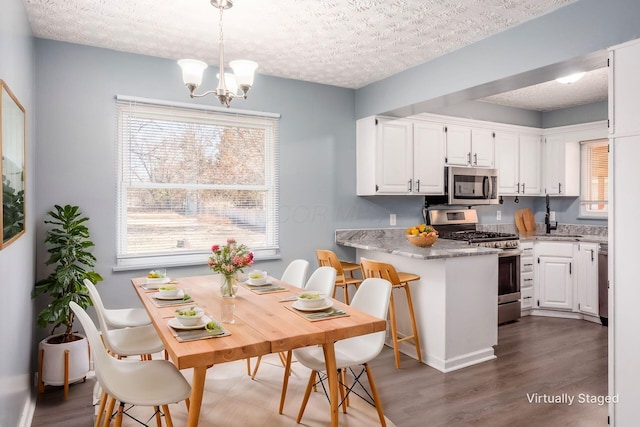 kitchen with white cabinetry, decorative light fixtures, a chandelier, a textured ceiling, and appliances with stainless steel finishes