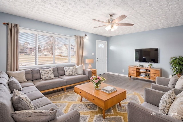 living room featuring hardwood / wood-style flooring, ceiling fan, and a textured ceiling