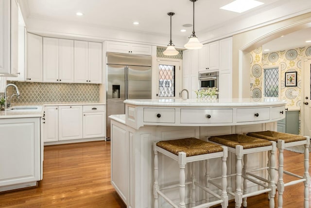 kitchen featuring a center island with sink, sink, stainless steel appliances, and white cabinets