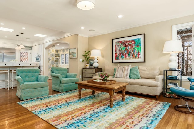 living room featuring ornamental molding, wood-type flooring, and a skylight