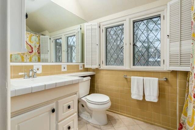 bathroom featuring tile patterned floors, tile walls, lofted ceiling, and vanity