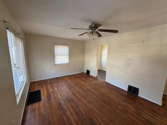 empty room featuring dark hardwood / wood-style flooring, ceiling fan, and a textured ceiling