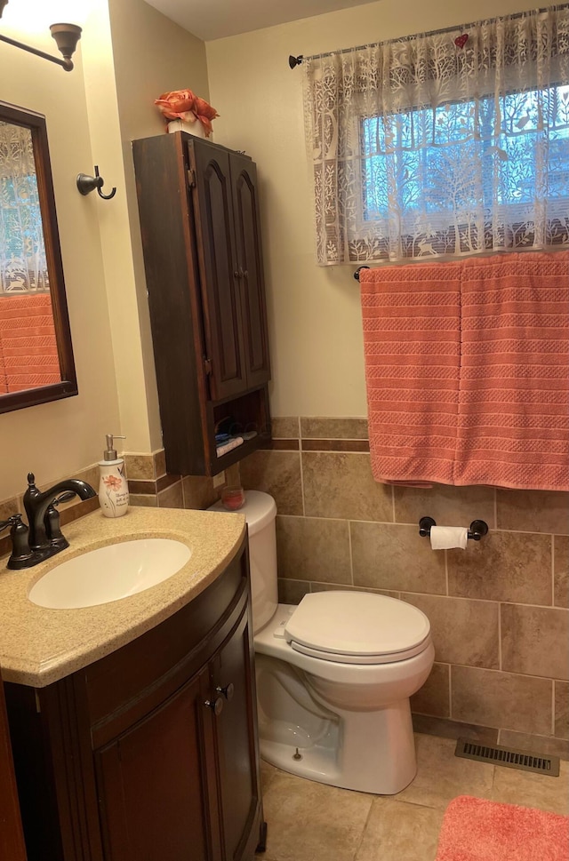 bathroom featuring tile patterned floors, vanity, toilet, and tile walls