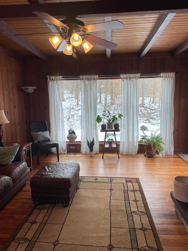 living room featuring a wealth of natural light, hardwood / wood-style floors, beam ceiling, and wood walls