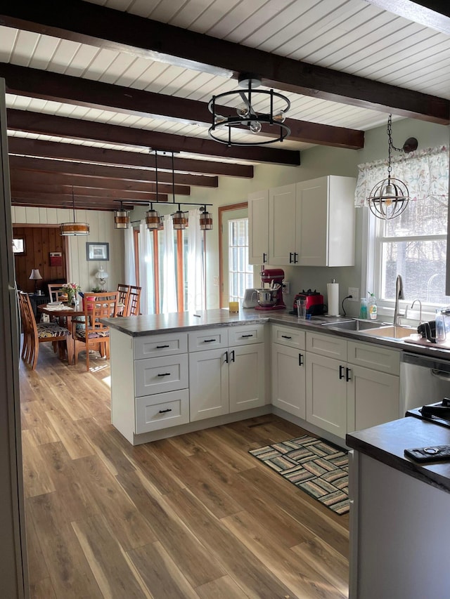 kitchen with white cabinetry, hanging light fixtures, dishwasher, kitchen peninsula, and hardwood / wood-style floors