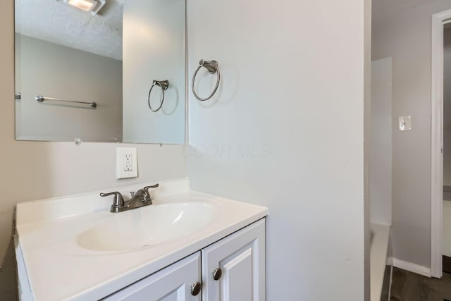 bathroom with vanity, a bathtub, and a textured ceiling