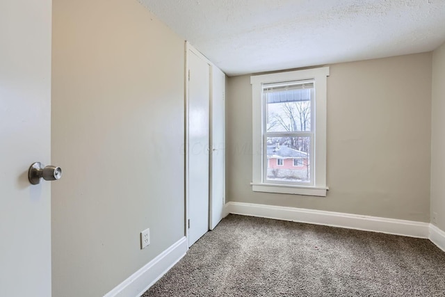 spare room featuring carpet and a textured ceiling