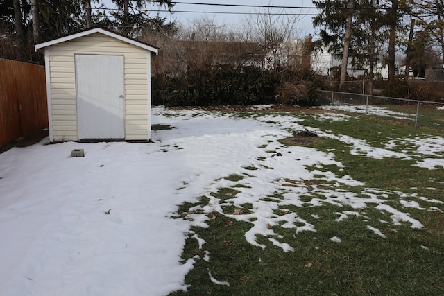 yard layered in snow featuring a storage shed