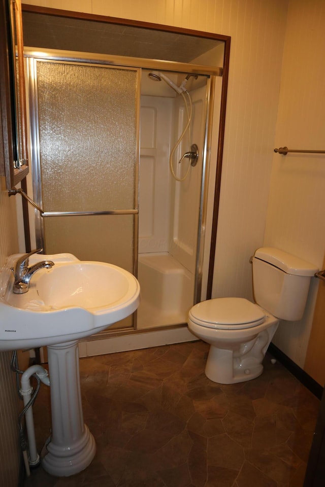 bathroom featuring toilet and a shower with shower door