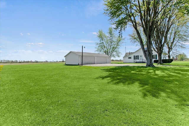 view of yard featuring a detached garage, driveway, and an outdoor structure