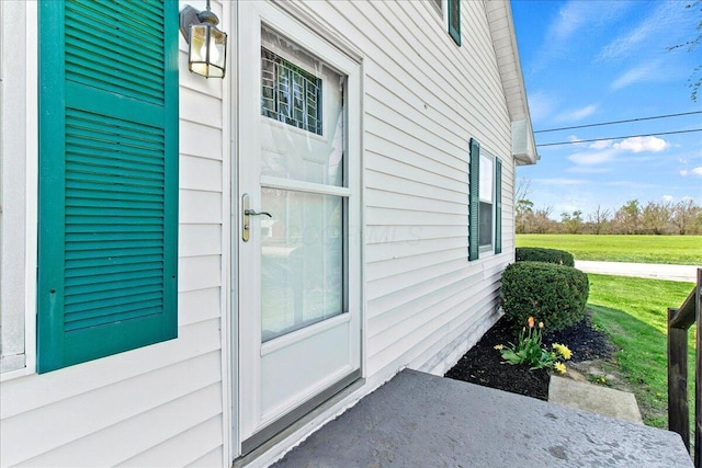 view of exterior entry featuring a lawn