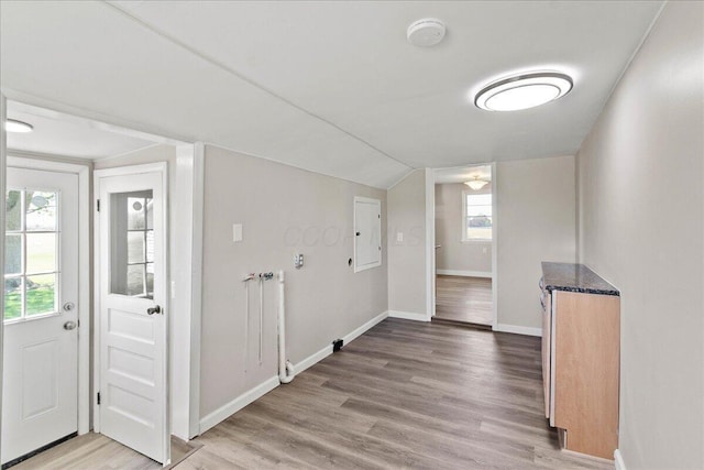 interior space featuring light wood-style floors, baseboards, and vaulted ceiling