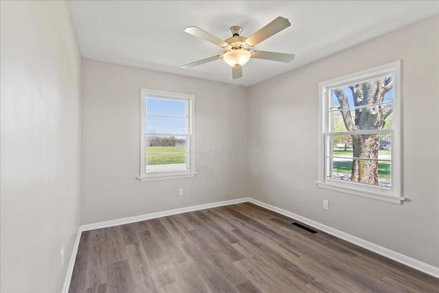 empty room with baseboards, ceiling fan, wood finished floors, and visible vents