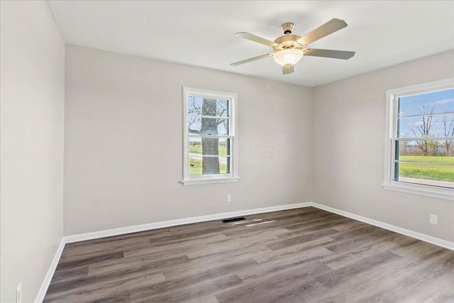 unfurnished room featuring visible vents, wood finished floors, and a wealth of natural light