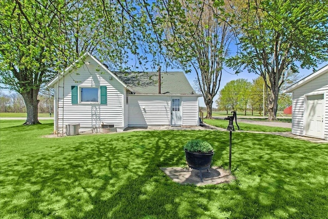 back of property featuring a yard and central AC