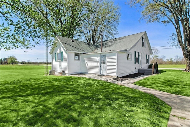exterior space featuring a lawn, a shingled roof, and cooling unit