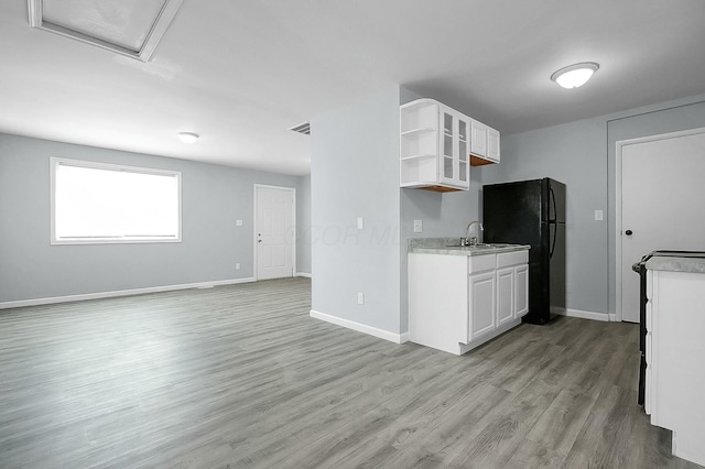 kitchen with black refrigerator, sink, white cabinets, and light hardwood / wood-style floors