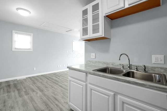 kitchen with white cabinetry, sink, and light wood-type flooring