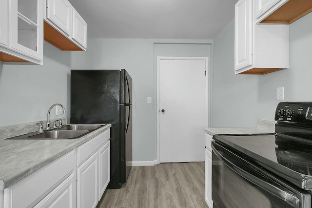 kitchen featuring white cabinetry, sink, black appliances, and light wood-type flooring