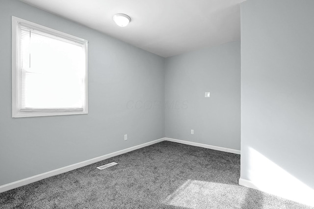 spare room with dark colored carpet