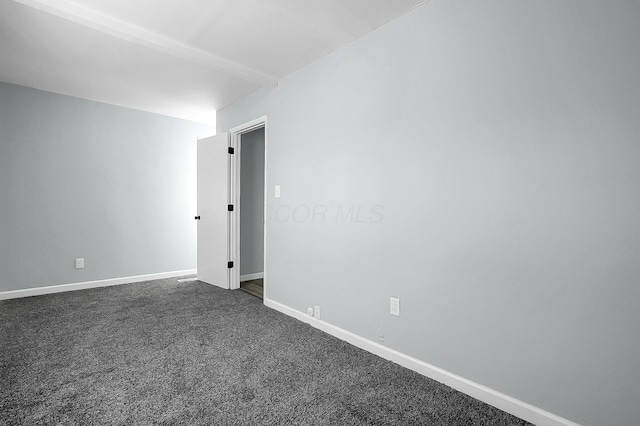 spare room with dark colored carpet