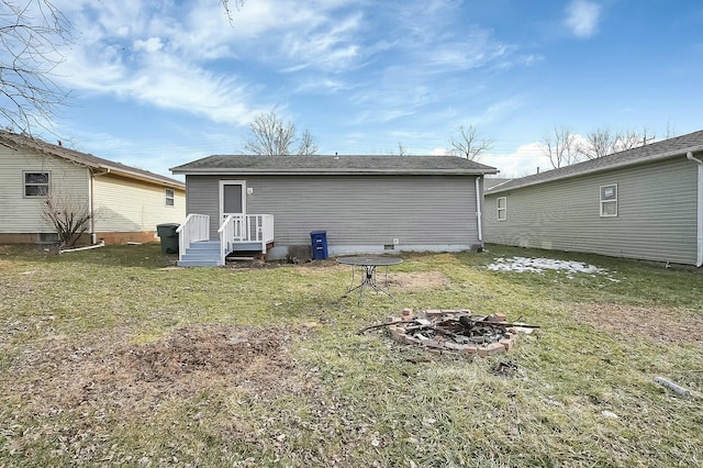 back of property featuring an outdoor fire pit and a yard