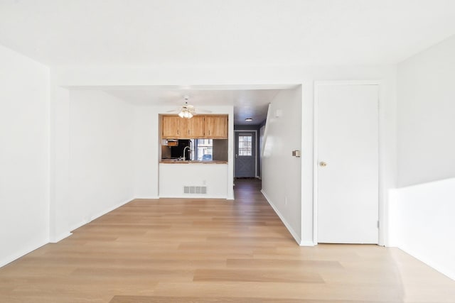 interior space with ceiling fan, sink, and light hardwood / wood-style floors