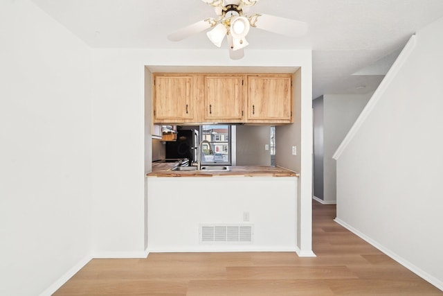 kitchen featuring sink, light hardwood / wood-style flooring, ceiling fan, black fridge, and light brown cabinets