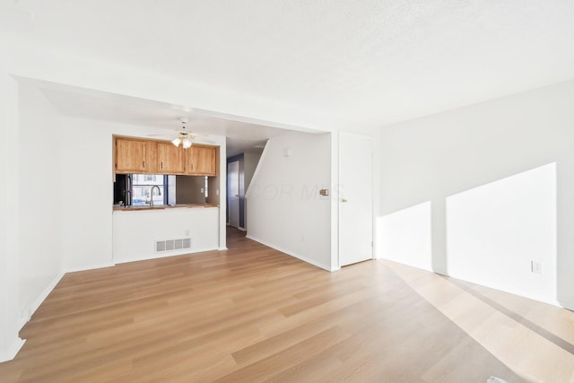 unfurnished living room with sink and light hardwood / wood-style flooring