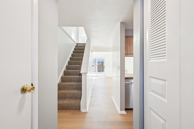 stairs featuring hardwood / wood-style floors and a textured ceiling