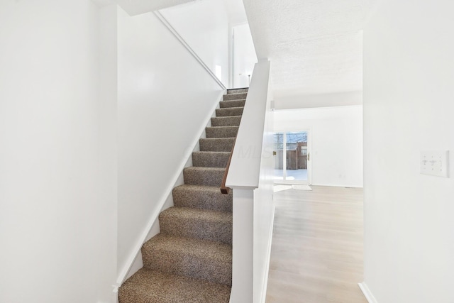 staircase featuring hardwood / wood-style floors and a textured ceiling