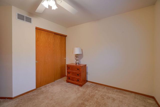 unfurnished bedroom featuring ceiling fan, a closet, and light carpet