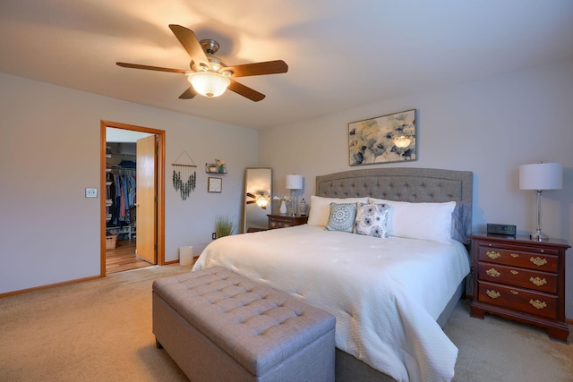 bedroom with ceiling fan, a spacious closet, a closet, and light carpet