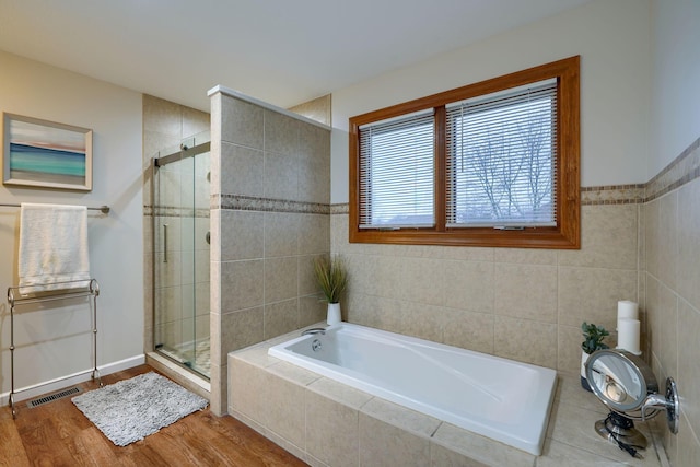 bathroom featuring tile walls, hardwood / wood-style flooring, and shower with separate bathtub